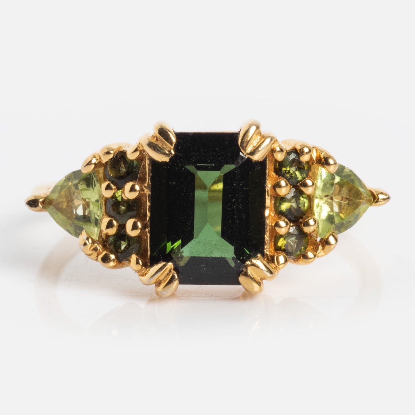The Green with Envy Topaz and Peridot Regal Ring features a 14k gold vermeil band with a rectangular green topaz center, flanked by triangular peridots and round accents on each side—ideal for lovers of bold statement rings.