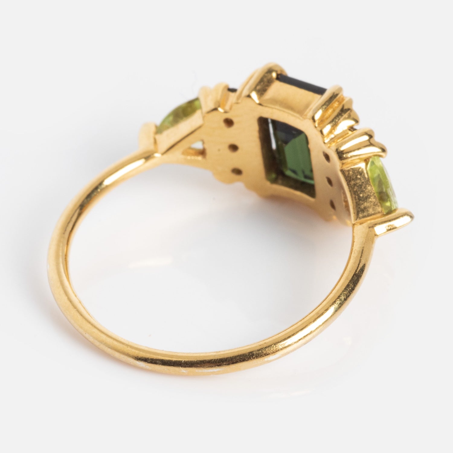 The Green with Envy Topaz and Peridot Regal Ring features a rectangular green topaz center stone flanked by two peridots, all set in 14k gold vermeil, displayed from an angled side view against a white background.