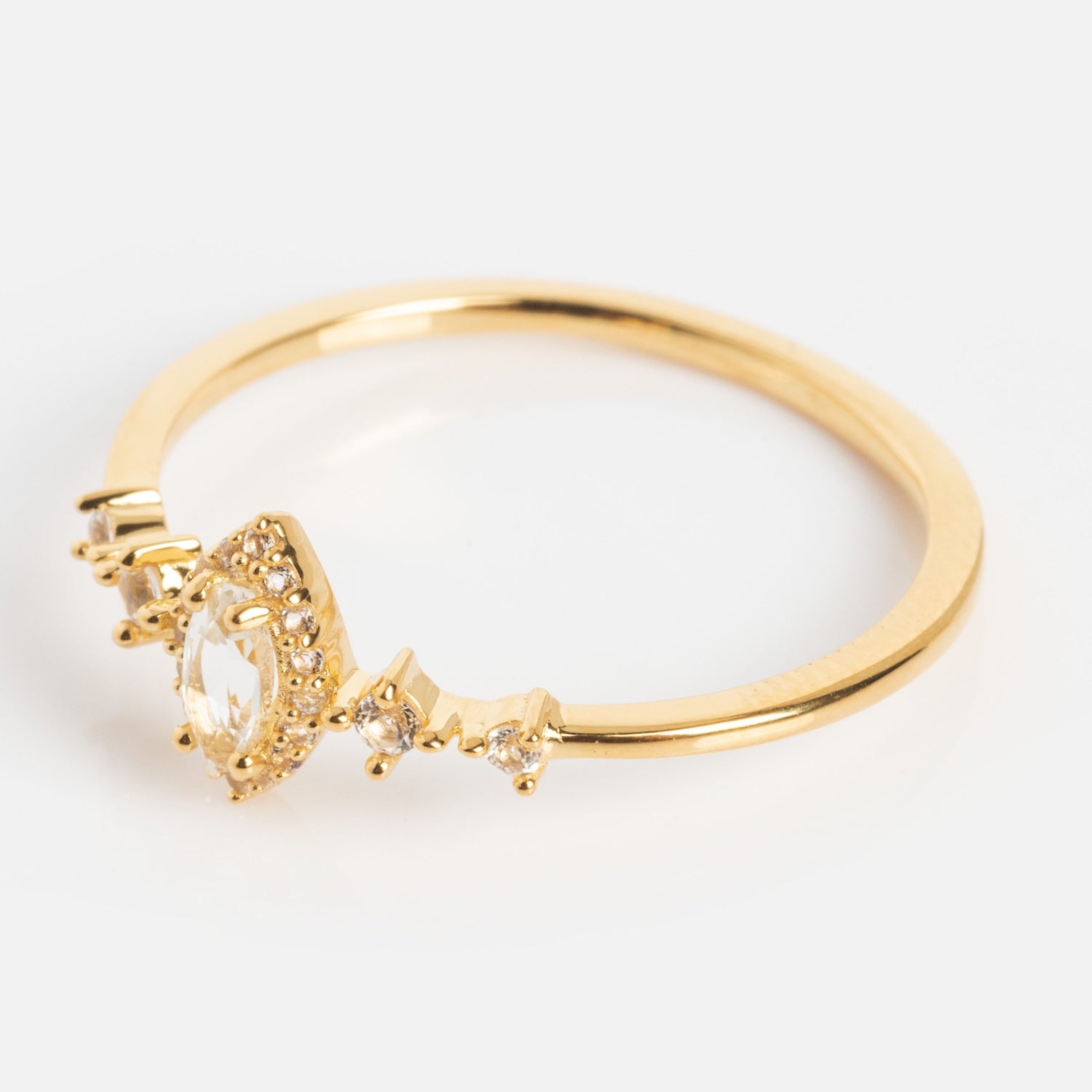 The White Topaz Harlow Ring is a delicate 18k Gold Vermeil marquise ring with a clear center gemstone, surrounded by small clear stones and three side accents, shown on a white background.
