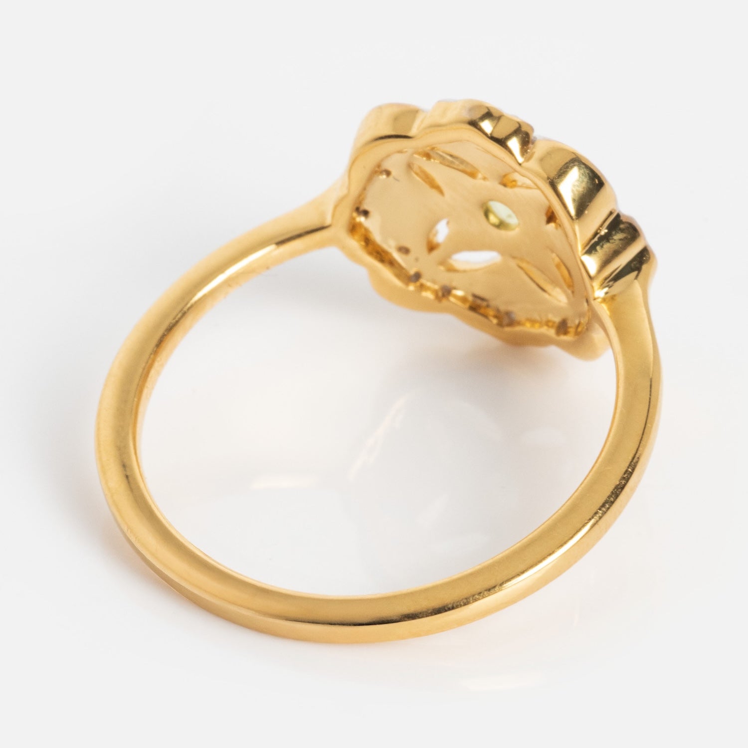 The Floral Art Deco Inspired Peridot Ring features a flower-shaped setting and a smooth, shiny band, shown at an angle to highlight the underside of the design against a white background.