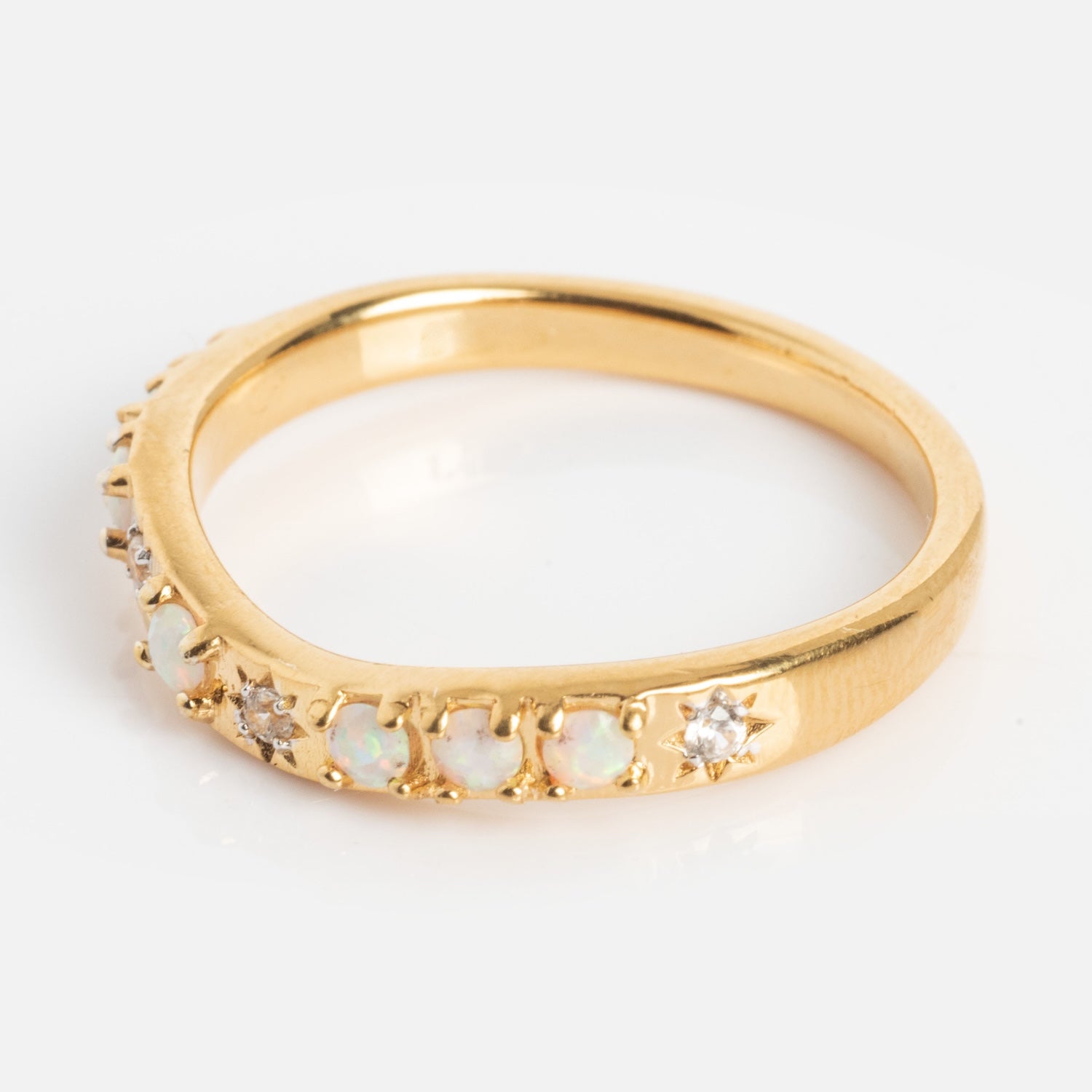 The Opal Stacking Wave Ring showcases a row of alternating small opals and clear gemstones set in gold, displayed on a plain white background.