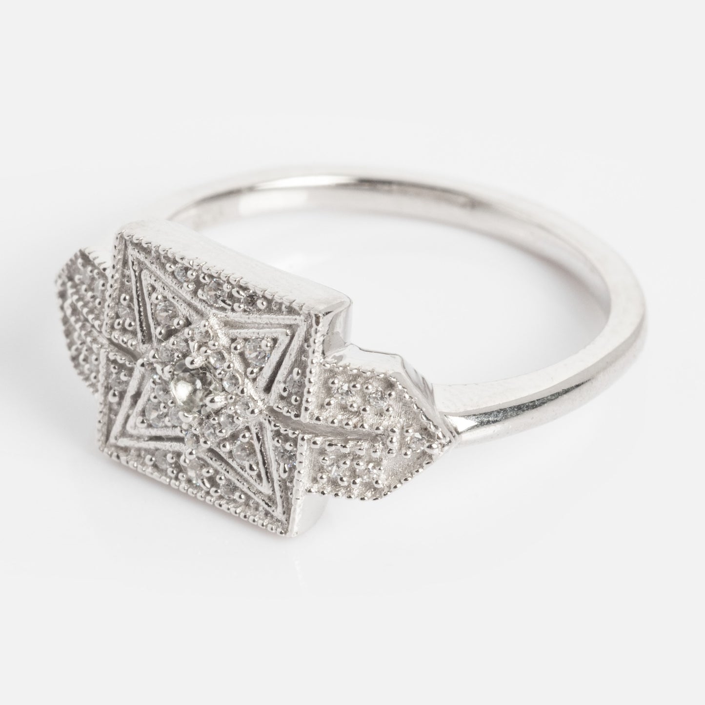 The Art Deco Inspired Statement Ring is a silver ring with a square top, featuring an intricate geometric star pattern and small raised dots, shown on a plain white background.