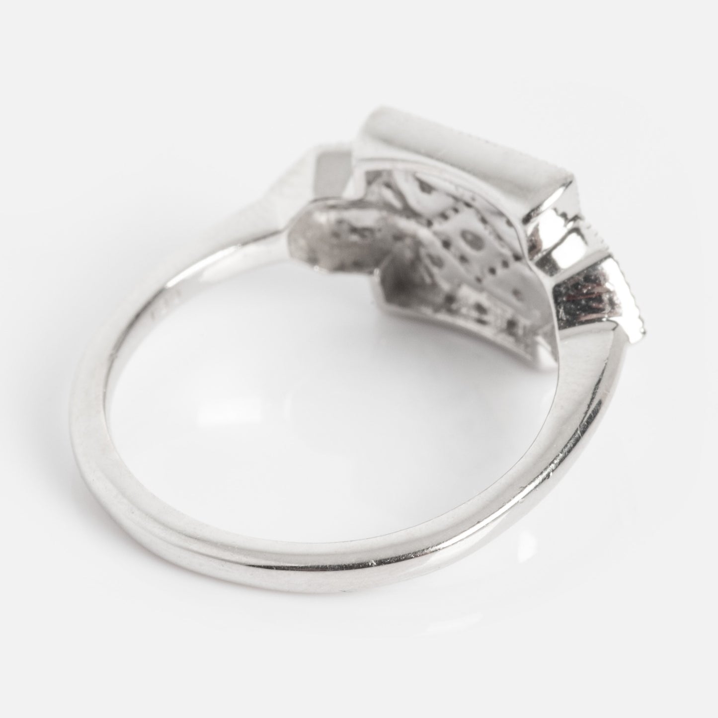 The Art Deco Inspired Statement Ring features a flat, rectangular silver setting, shown from the back to reveal the band and intricate metalwork beneath, displayed on a white background.