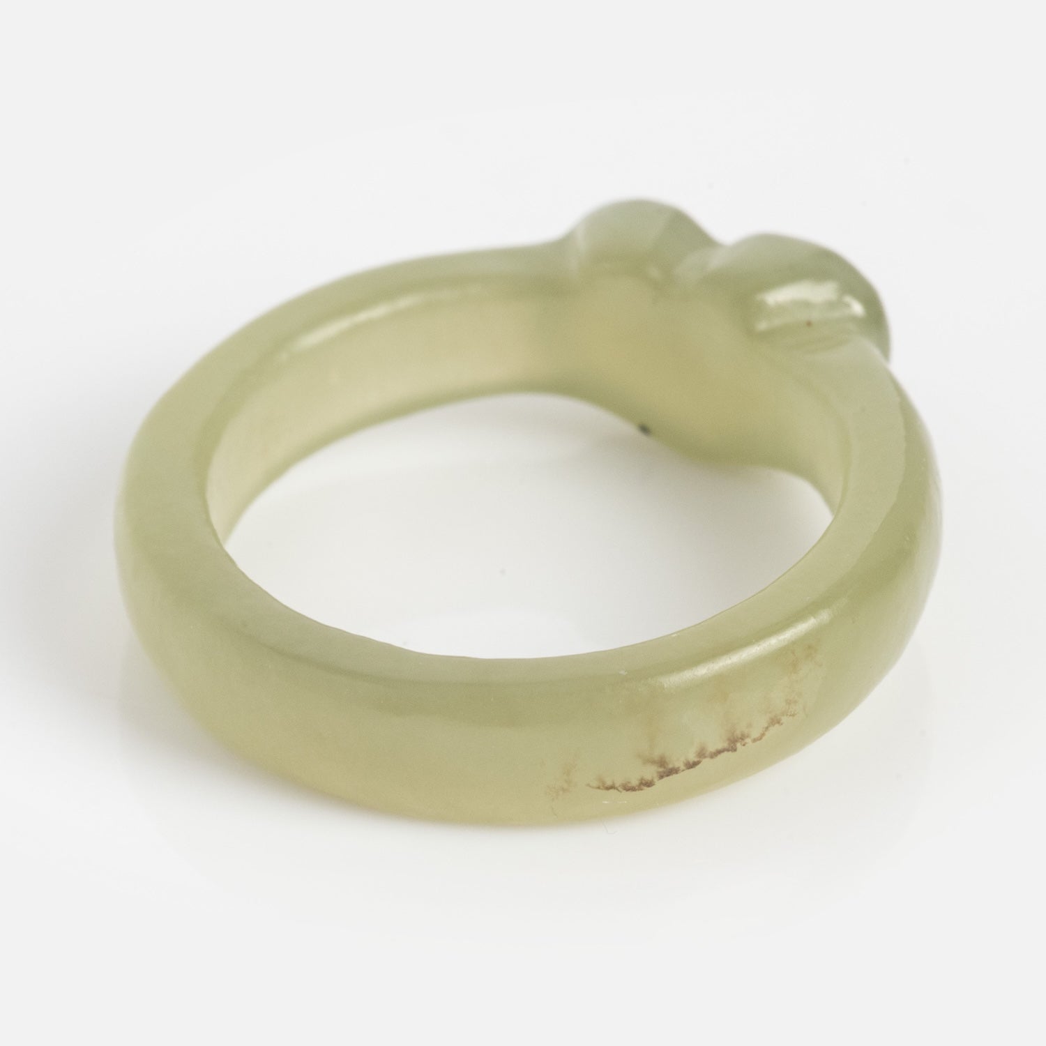 The Heart Jade Ring features light green jade with a smooth, 3.5 mm rounded band, a slightly uneven surface, a small raised area at the top, and a natural brownish mark on the side.
