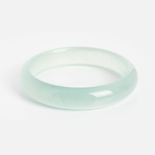 The Pool Blue Jade Stone Bangle, with a smooth polished finish, is displayed on a white background. It measures 13.5 mm in width and has a 2.4-inch opening for comfortable wear.