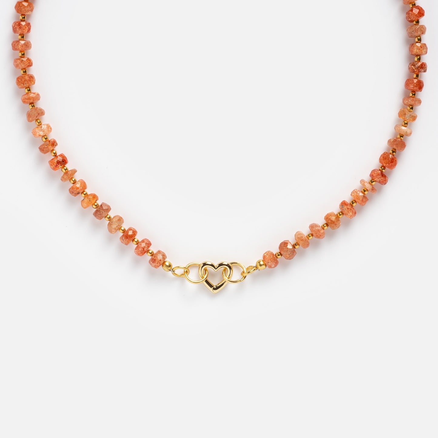 The Customizable Beaded Gemstone Charm Holder Necklace features small, round orange sunstone beads and a gold interlocking heart clasp, shown on a plain white background.