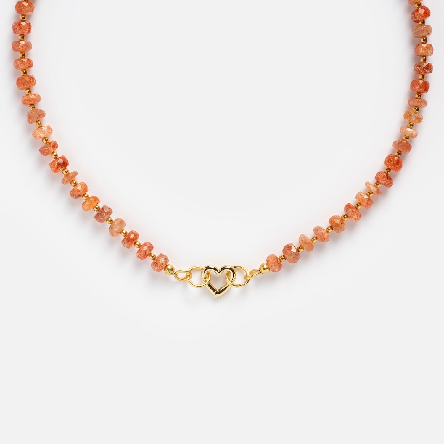 The Customizable Beaded Gemstone Charm Holder Necklace features small, round orange sunstone beads and a gold interlocking heart clasp, shown on a plain white background.