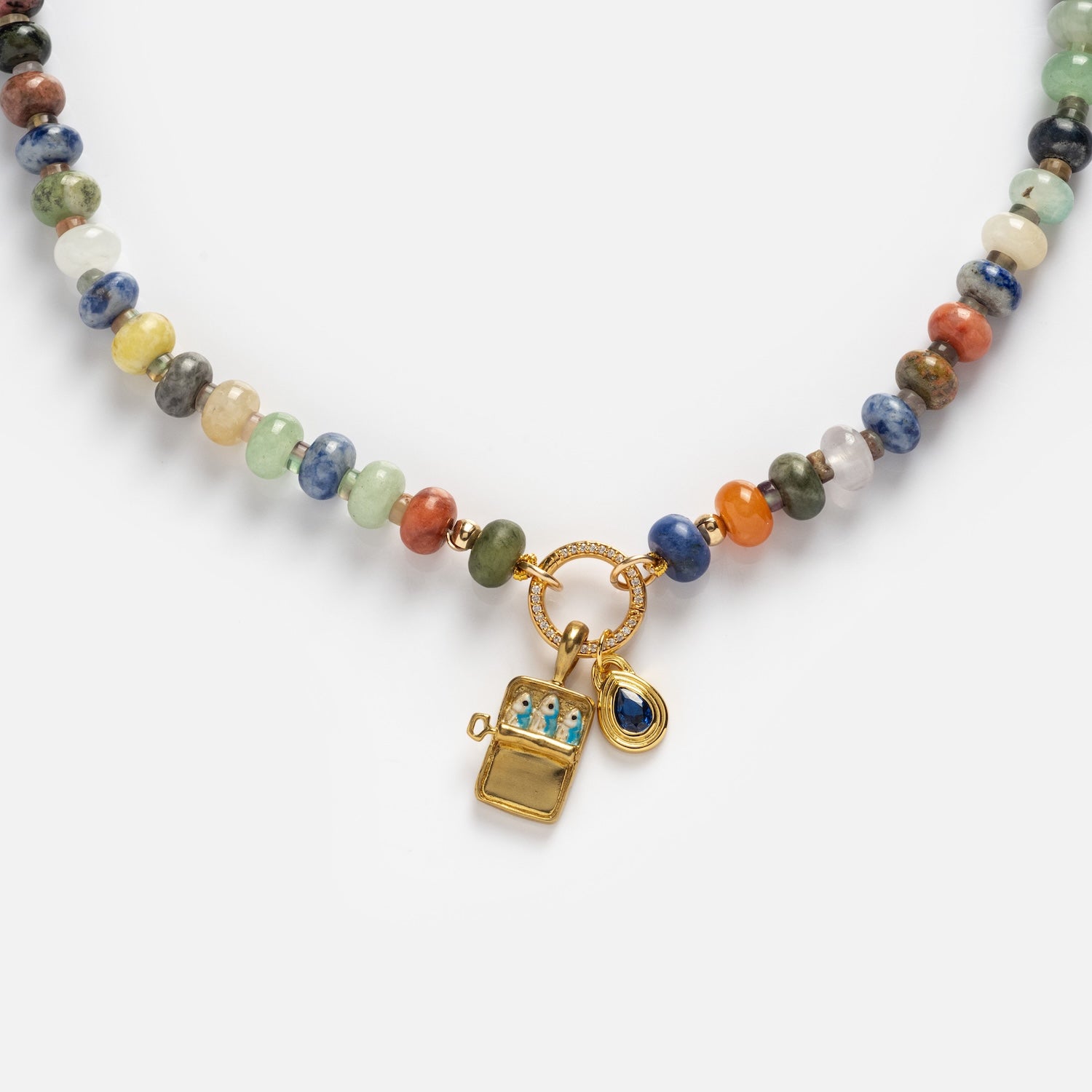 The Macey Customizable Beaded Charm Holder Necklace features colorful beads, a gold toggle clasp, and two gold charms: a lighter-shaped charm with blue gemstones and a small blue teardrop gem charm.