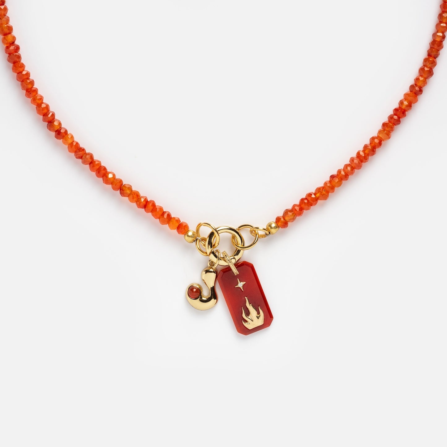 The Customizable Beaded Gemstone Charm Holder Necklace features orange beads, a gold clasp, and two charms: a gold swirl with a red stone and a red pendant adorned with a gold flame and star design.