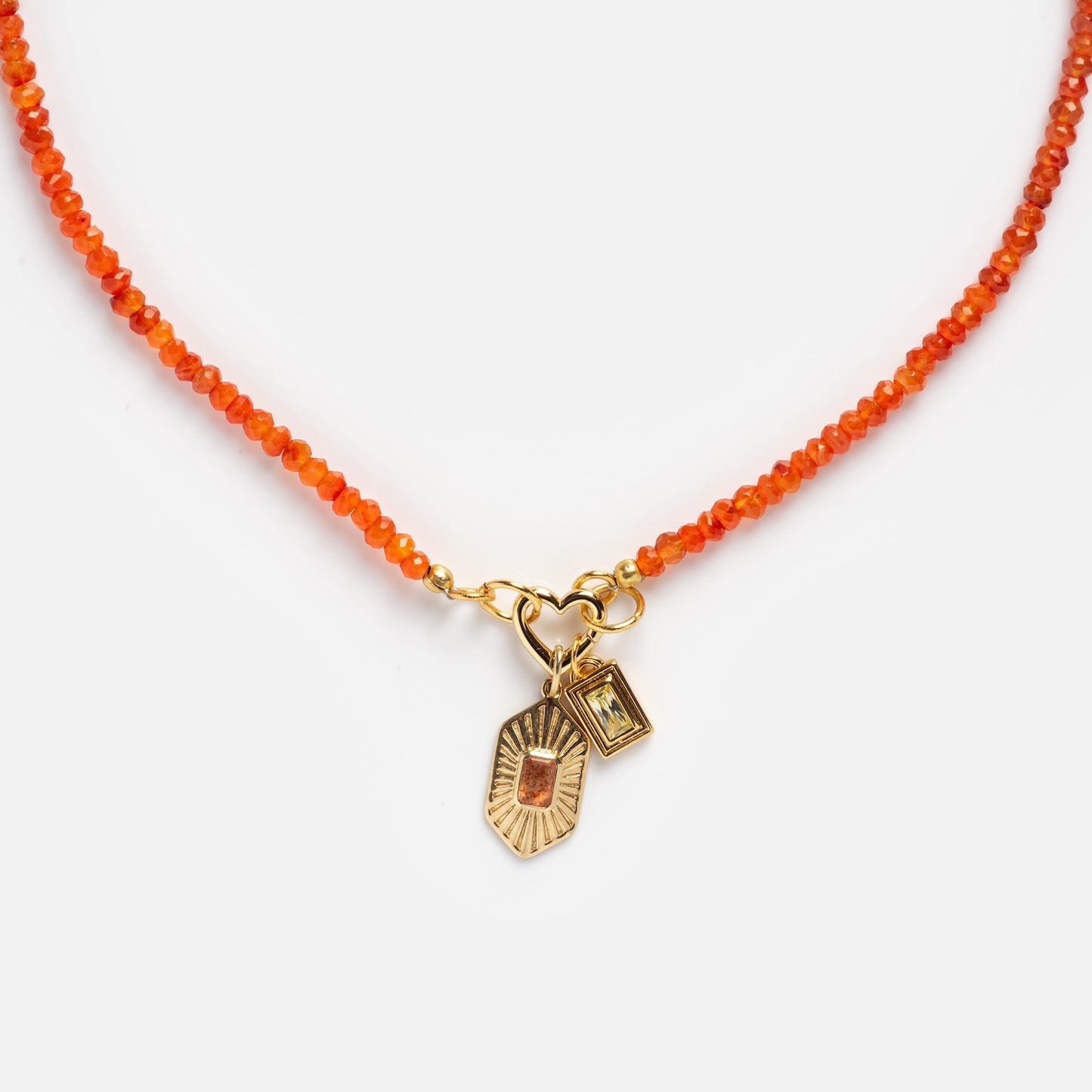 The Customizable Beaded Gemstone Charm Holder Necklace features orange beads and two gold charms: a rectangular charm with a gemstone and a sunburst charm with an orange stone, shown on a white background.