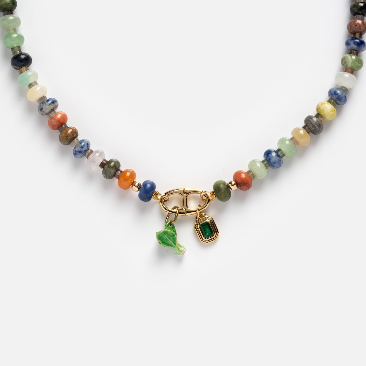 The Macey Customizable Beaded Charm Holder Necklace features multicolored round stones, a gold clasp with a small green glass leaf charm, and a rectangular green gemstone charm, displayed on a white background.
