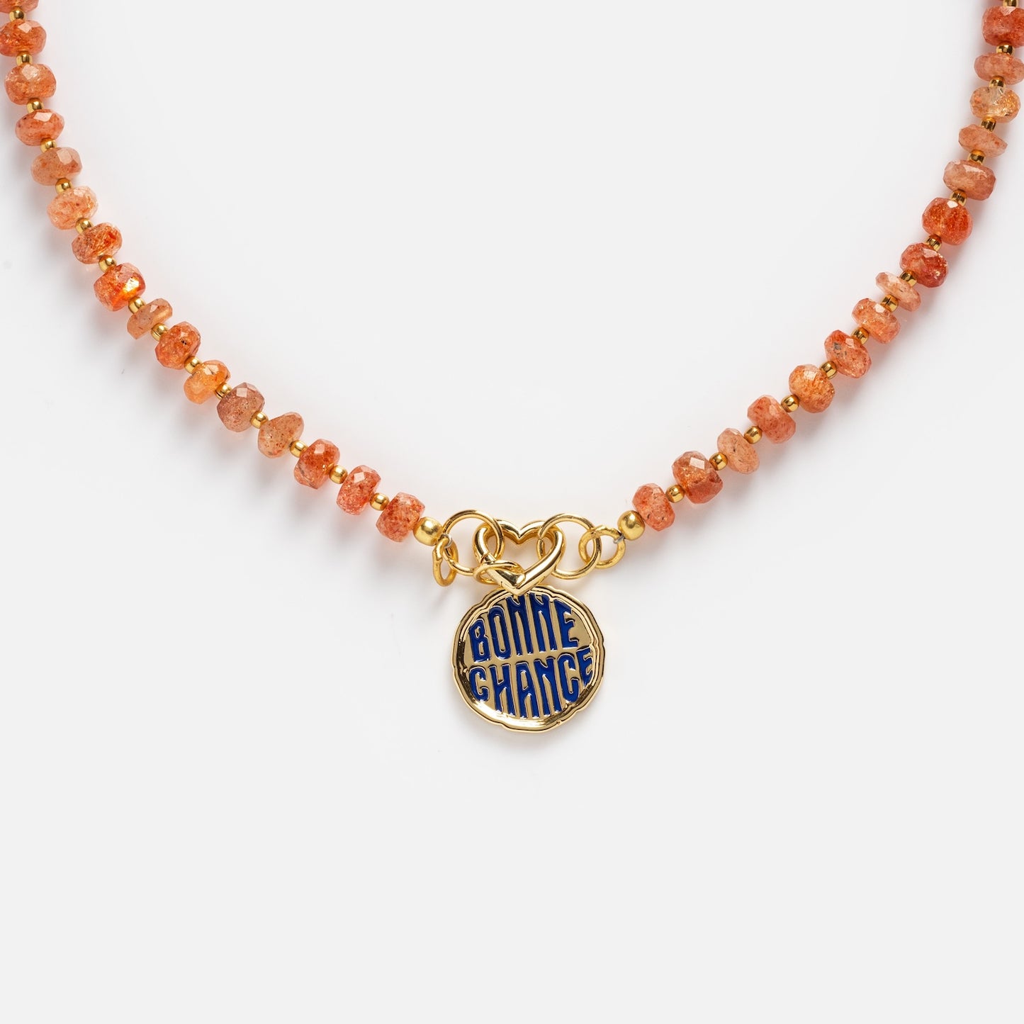 Close-up of the Customizable Beaded Gemstone Charm Holder Necklace featuring an orange beaded design and a round gold pendant with blue enamel reading "BONNE CHANCE," displayed on a plain white background.