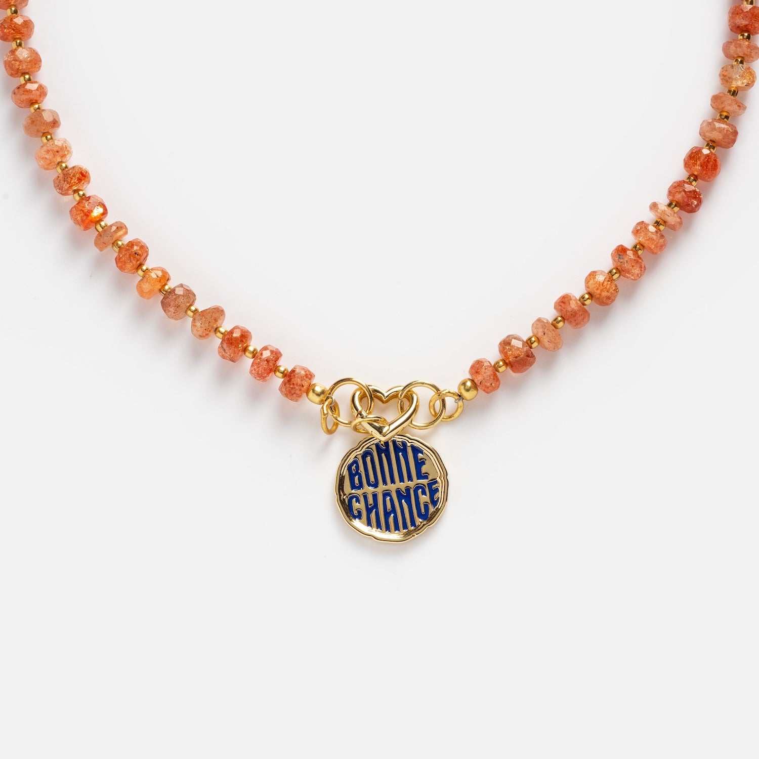 Close-up of the Customizable Beaded Gemstone Charm Holder Necklace featuring an orange beaded design and a round gold pendant with blue enamel reading "BONNE CHANCE," displayed on a plain white background.