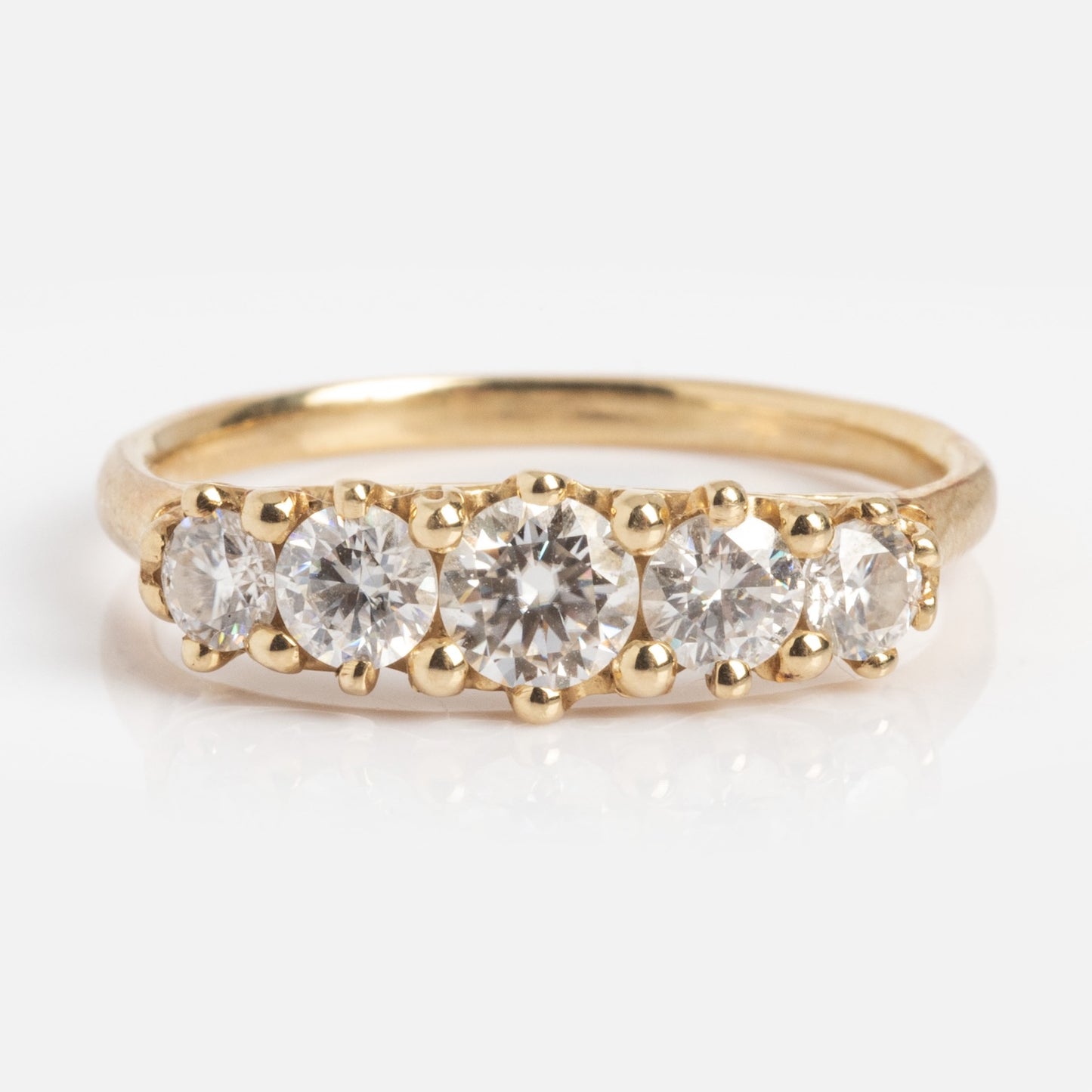 The Anniversary Band features a 1.7 mm gold band set with five round moissanite stones totaling 0.78 ctw, arranged in a row and shown from the front on a white background.