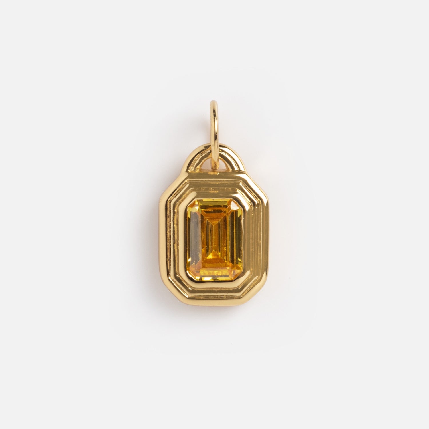 The Monroe Birthstone Charm is a gold pendant with an emerald-cut yellow gemstone at the center, featuring an octagonal, art deco-inspired design and a top loop for attaching to a chain.