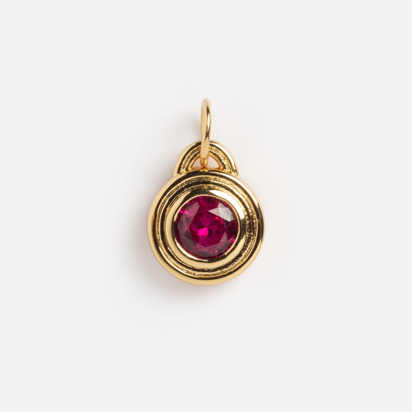 The Monroe Birthstone Charm is a small gold pendant featuring a round, faceted red gemstone at its center, displayed against a plain white background.