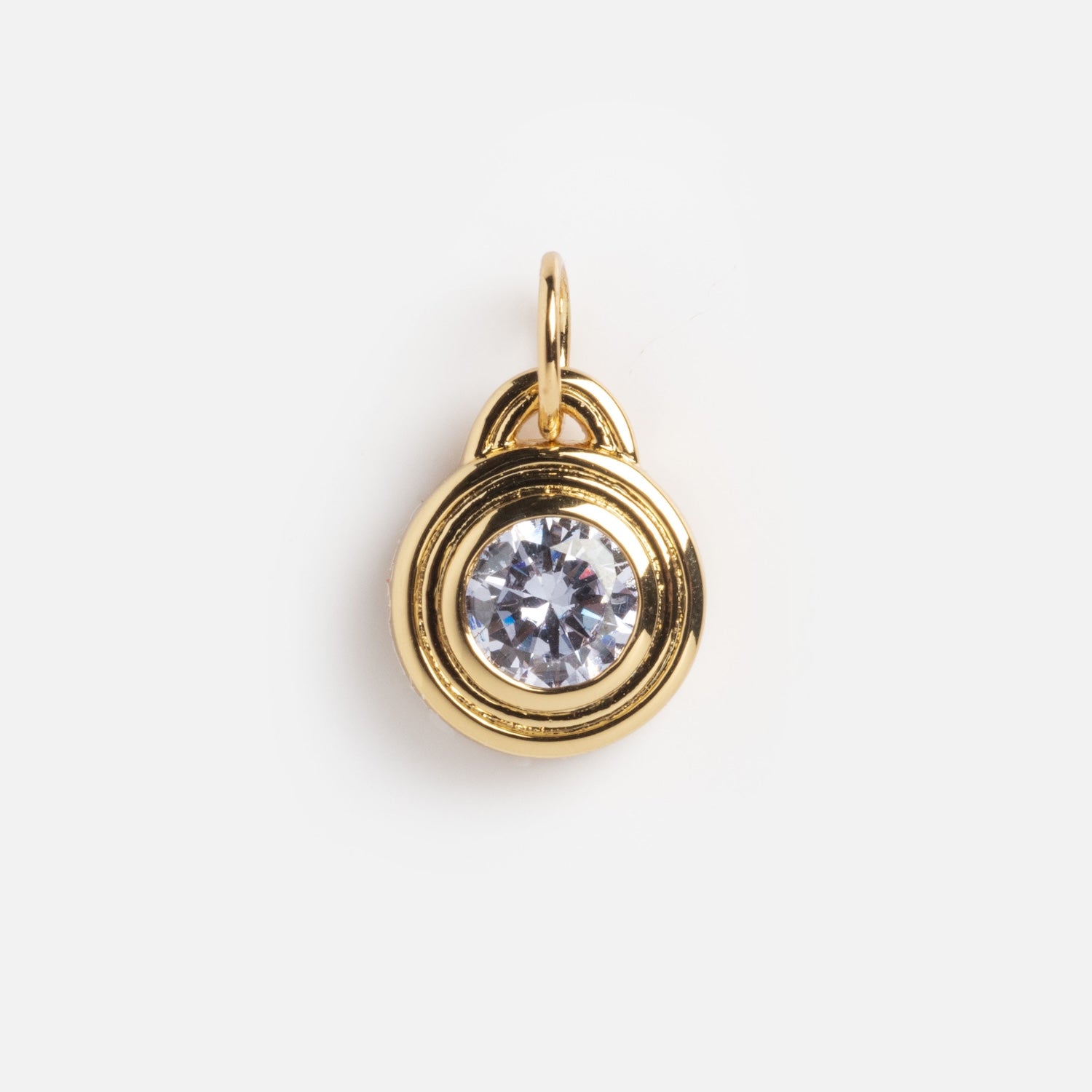 The Monroe Birthstone Charm is a small gold pendant with a clear round gemstone at the center, bordered by smooth gold and a top loop for attaching to a chain.