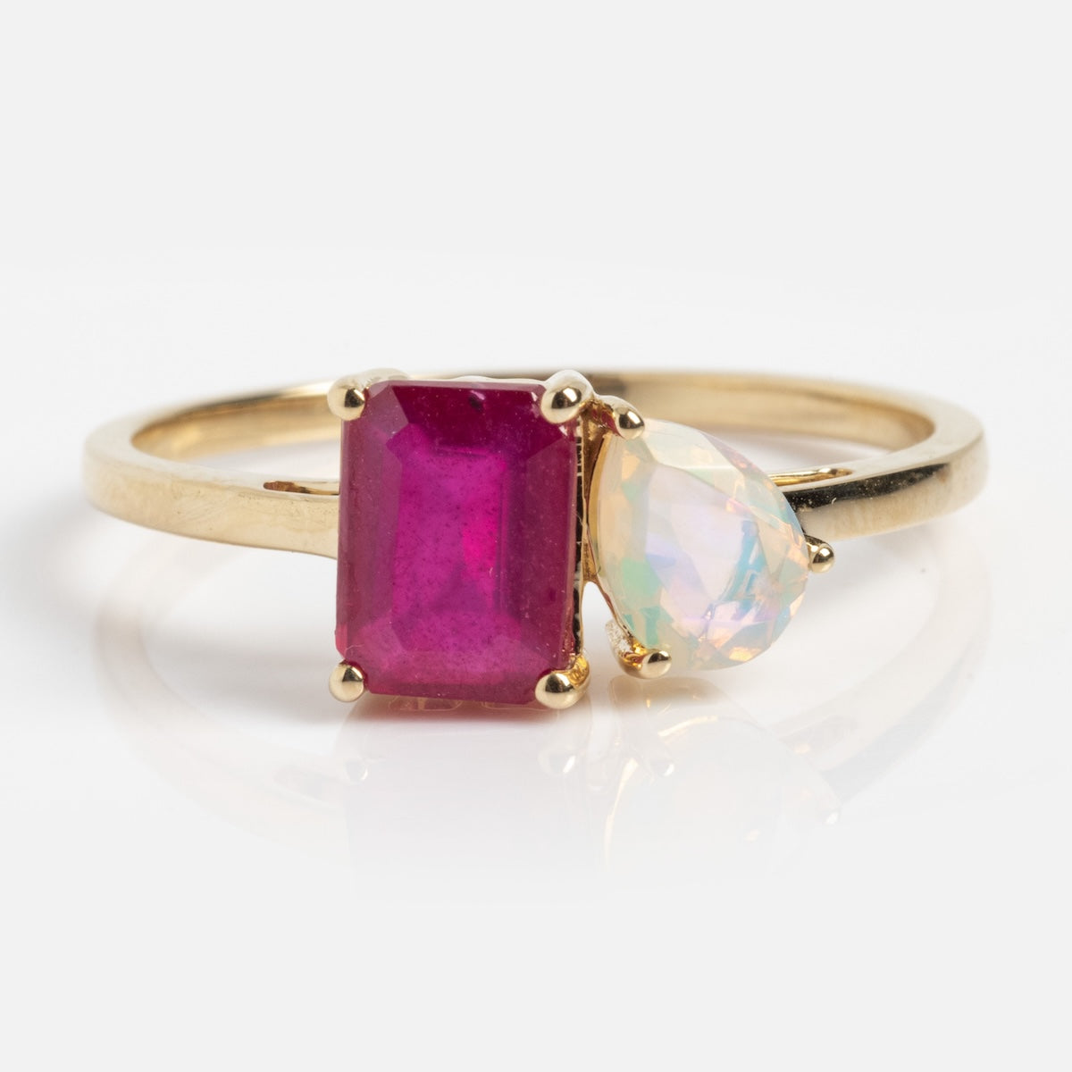 The Ruby Opal Toi et Moi Ring Sample Size 12 features a 9k solid yellow gold band with an octagon step cut deep pink gemstone and a pear brilliant cut iridescent gemstone set side by side against a white background.