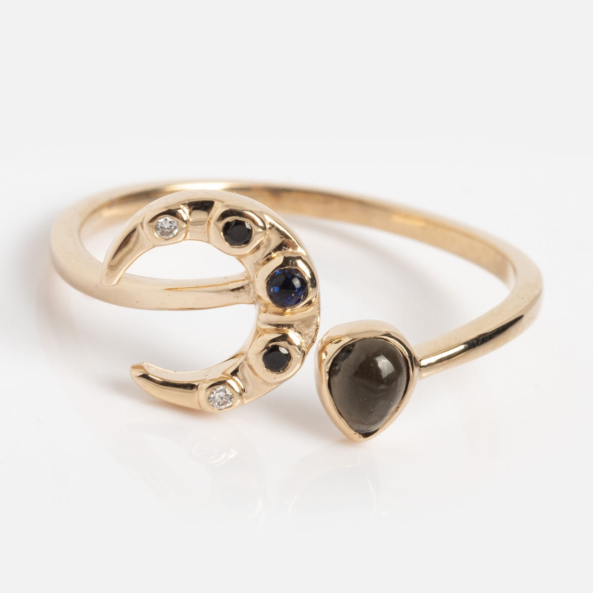 The Solid Gold Black Opal Crescent Moon Ring (Sample Size 7) features a crescent moon with dark and clear gemstones and a blue sunstone teardrop on an open band, beautifully displayed against a white background.