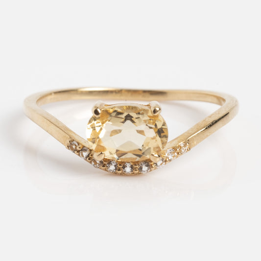 The Solid Gold Floating East West Citrine Ring (Sample Size 7) is crafted in 14k yellow gold with an oval citrine center and white topaz accents along the band, shown on a white background.