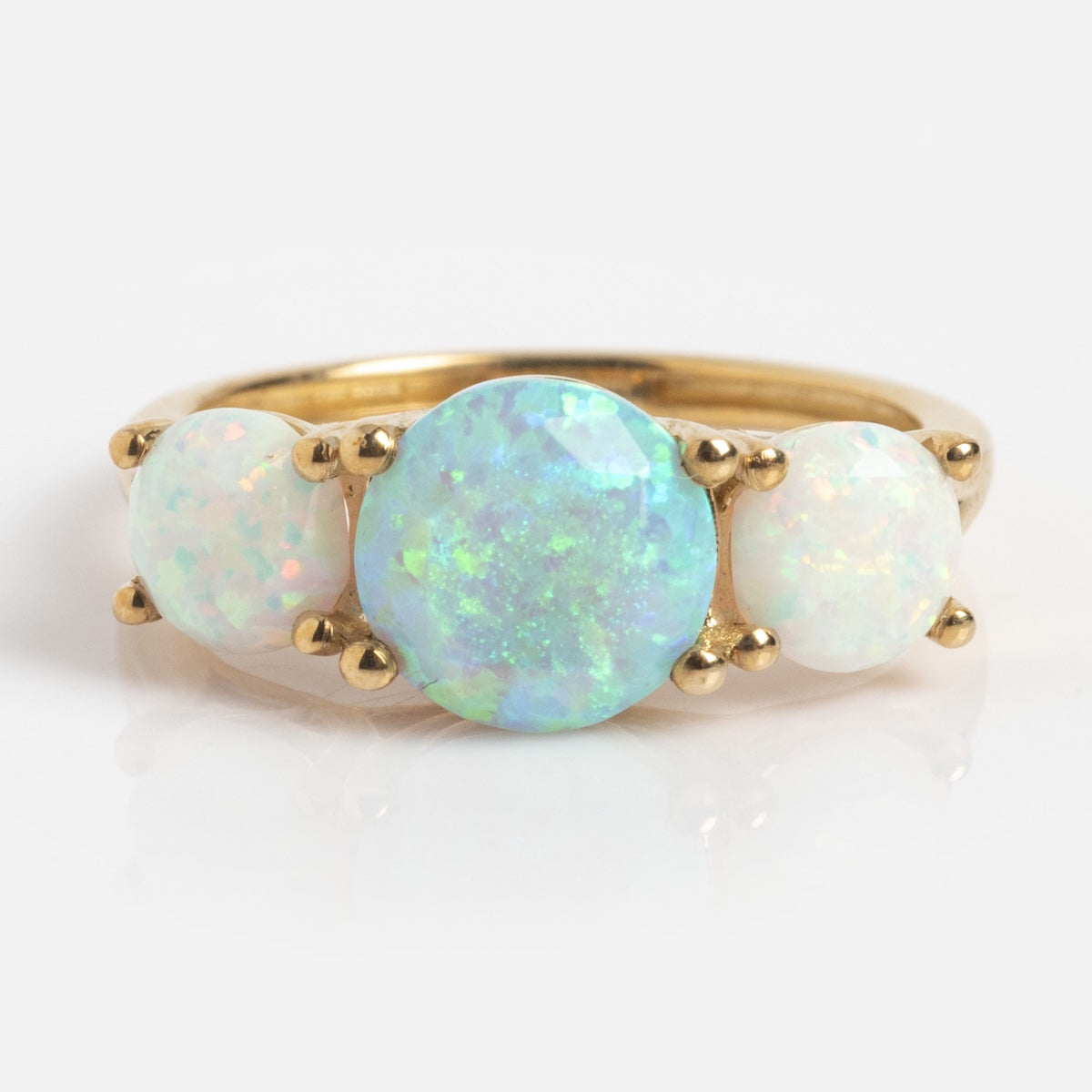 The Solid Gold Trilogy Birthstone Pinky Ring Opal (Sample Size 5) is crafted in 9k yellow gold and features three round synthetic opals, with a vibrant 7mm iridescent center stone.