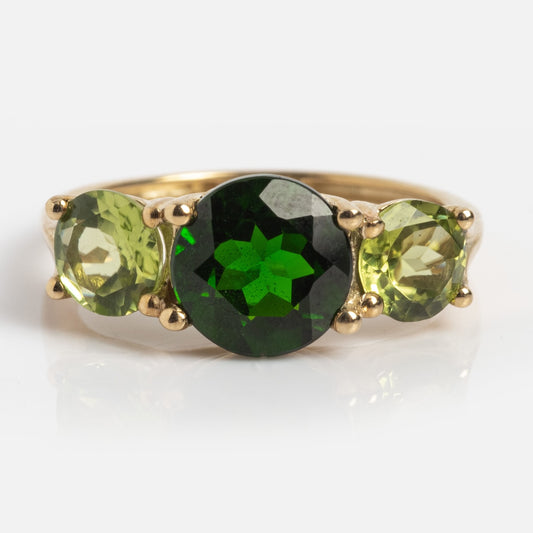 The Solid Gold Trilogy Birthstone Pinky Ring (sample size 5) features a large central round deep green diopside flanked by two lighter green peridot gemstones, all set in 9k yellow gold with prongs and displayed on a white background.