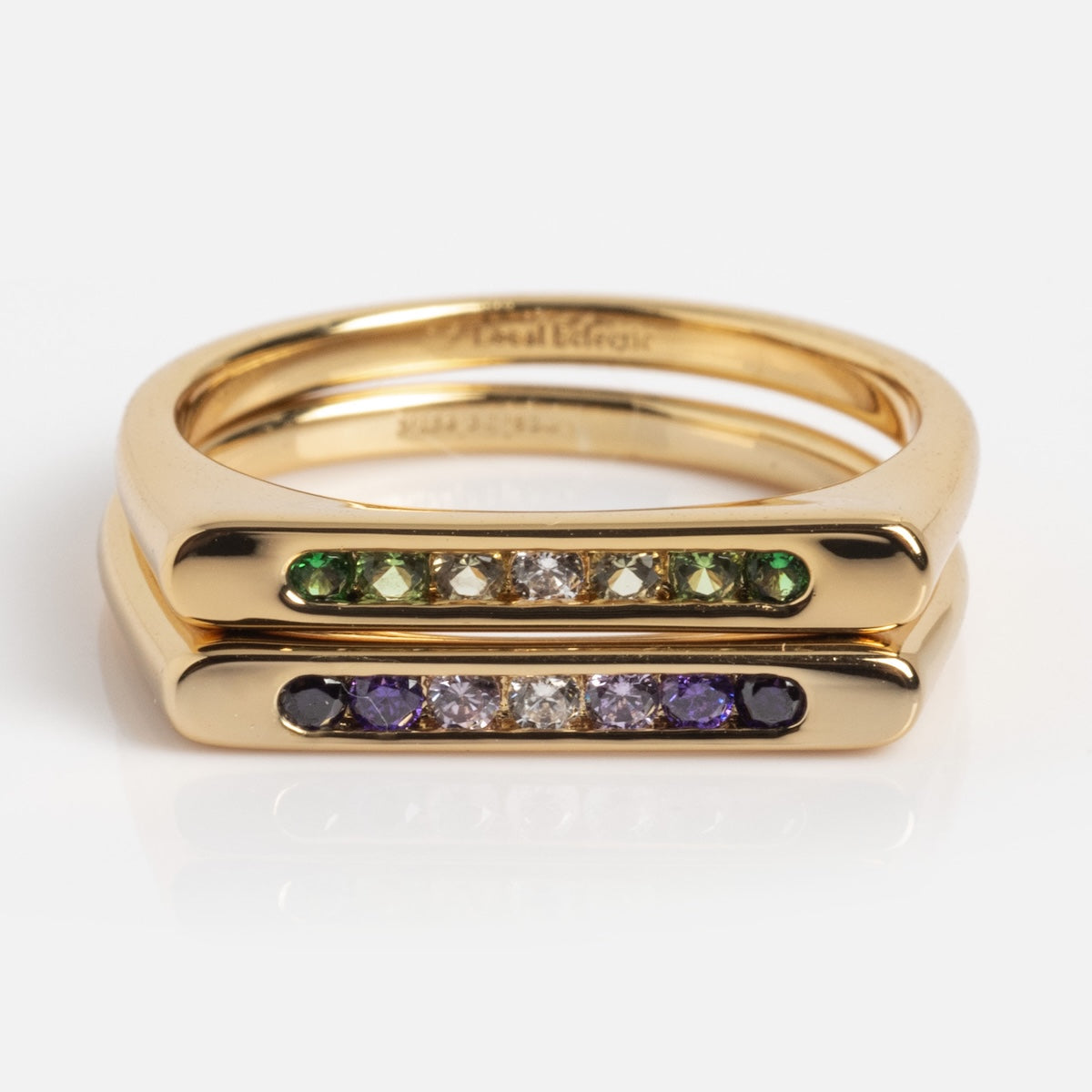 The Ombre Gem Duo Pinky Ring (Sample Size 5) features two stacked 14k yellow gold vermeil bands with rows of White CZ gemstones; the top has green and clear stones, and the bottom displays purple and clear stones in sleek bars.