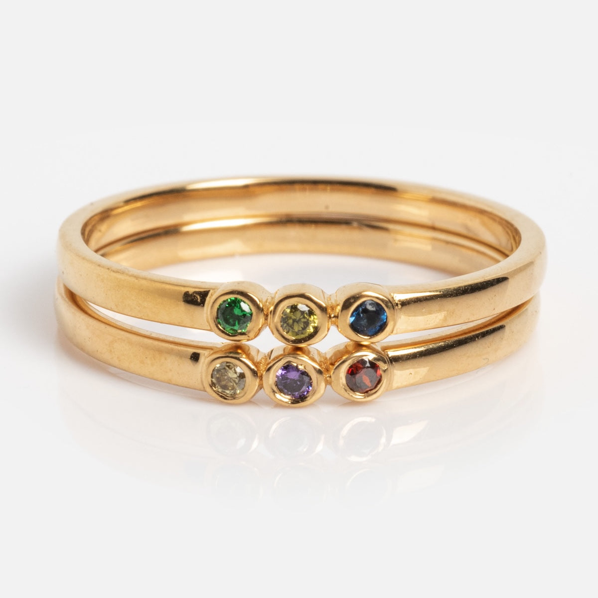 The Colorful Stacked Gem Drop Pinky Ring Sample Size 7 features three 14k yellow gold plated CZ rings stacked together, each displaying a small green, yellow, blue, purple, or red gemstone against a plain white background.