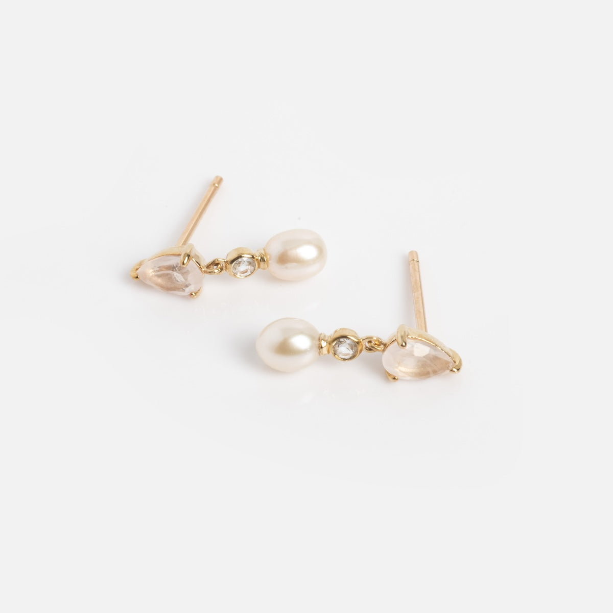 The Solid Gold Aquamarine Morganite and Pearl Drop Studs Sample features gold studs with teardrop-shaped aquamarine, round clear morganite, and a dangling freshwater pearl, shown on a white background.