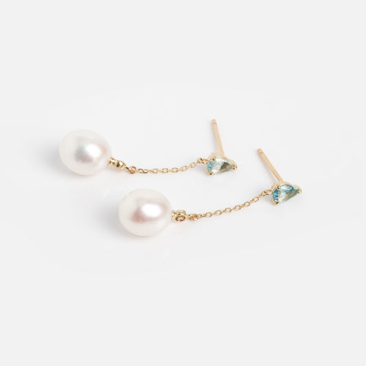 The Solid Gold Blue Topaz and Pearl Drop Earrings Sample features 9k gold drops with small Swiss Blue Topaz studs and large round white pearls on delicate chains, shown against a plain white background.