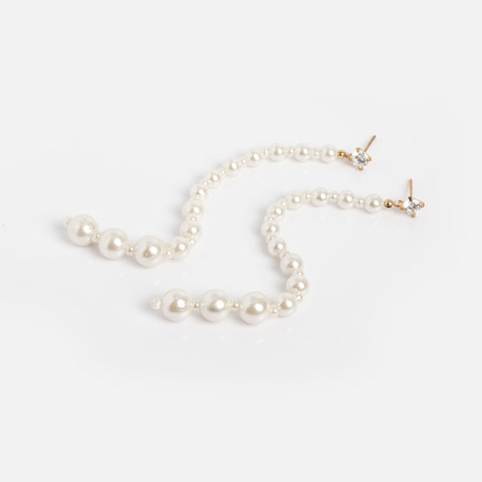 The Miami Vice Earrings Sample features long, dangling earrings with graduated white pearls and 14k vermeil posts accented by small sparkling stones, shown arranged on a plain white background.
