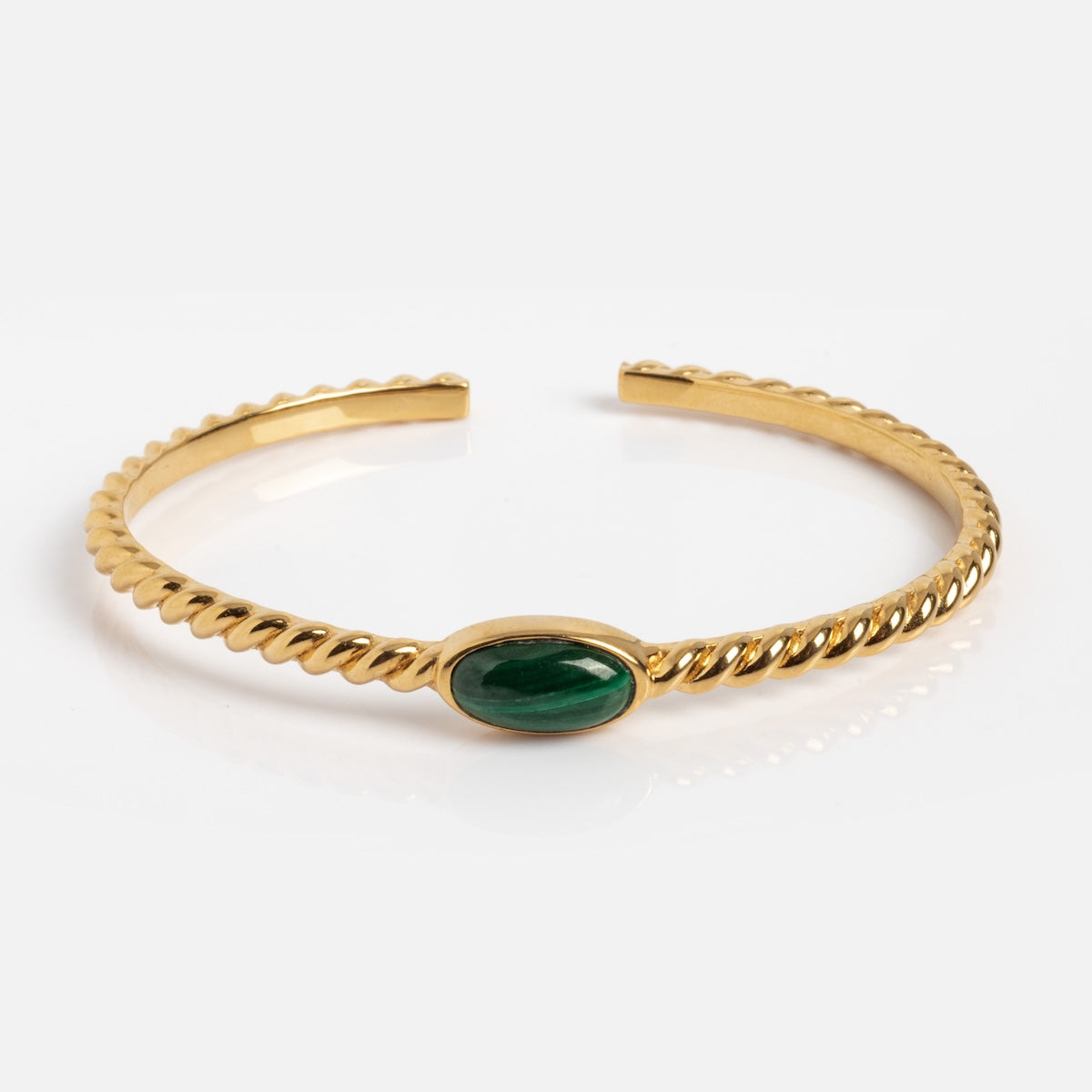 The Malachite Bangle Sample is an 18kt gold twisted open cuff bracelet with a central oval cabochon malachite gemstone, shown on a plain white background.