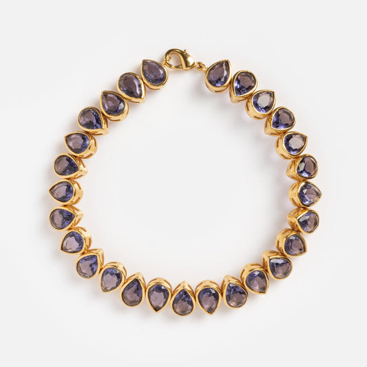 The Bezel Set Birthstone Tennis Bracelet February Sample features teardrop-shaped purple cubic zirconia gemstones in yellow gold-plated bezels, evenly spaced along the chain and displayed on a plain white background.