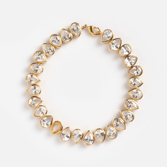 The Bezel Set Birthstone Tennis Bracelet April Sample is a yellow gold plated bracelet with alternating pear-shaped and round cubic zirconia gemstones in a symmetrical design, shown on a plain white background.