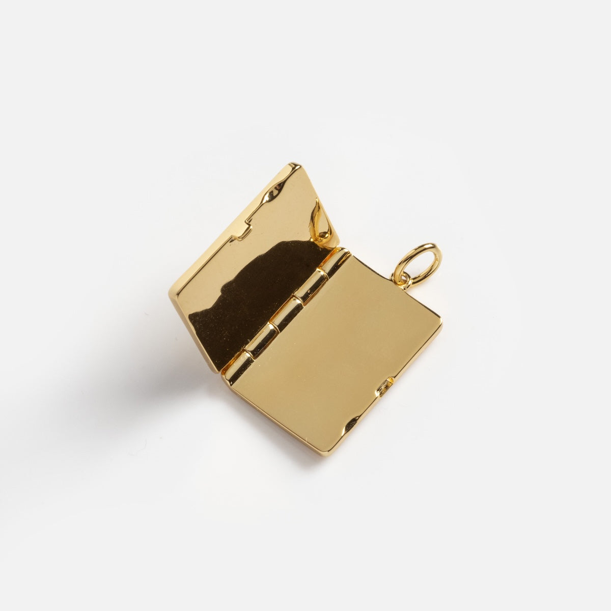 The Secret Gem Locket Charm Sample is a shiny gold locket shaped like an open book, featuring a small loop for attaching to a chain, displayed on a plain white background.