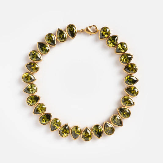 The Bezel Set Birthstone Tennis Bracelet August Sample is yellow gold plated, featuring alternating pear-shaped and round green stones with cubic zirconia accents in a circular pattern and a lobster clasp, shown on a white background.