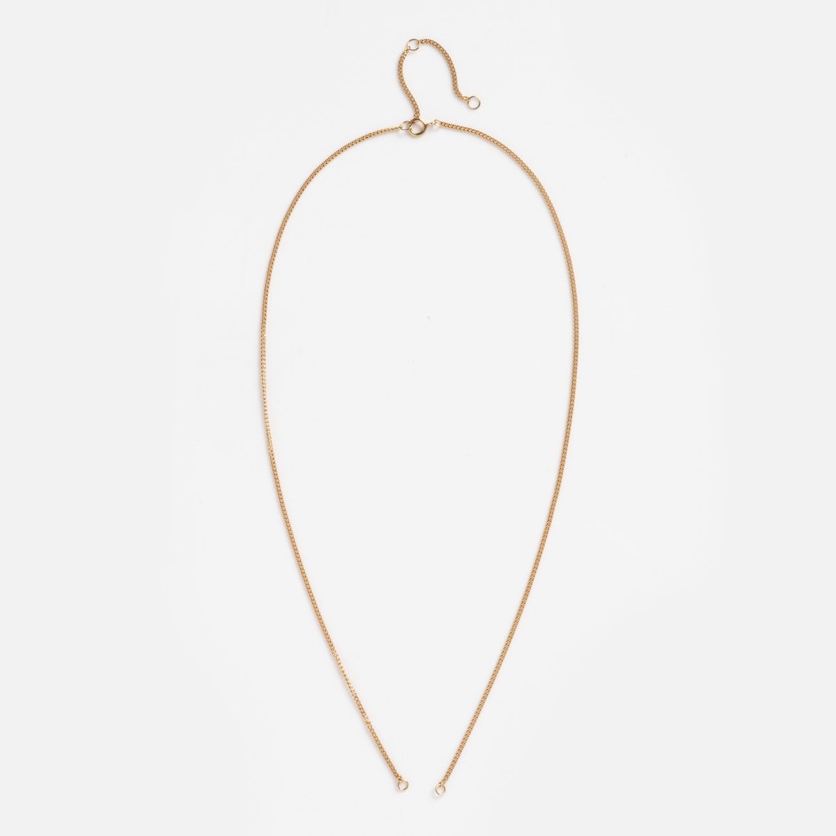 The Solid Gold Perfect Start Charm Holder Curb Chain Sample is a delicate 9k solid gold necklace laid flat on white, forming an elongated oval with small end loops, a charm clip detail, and a hook clasp at the top.