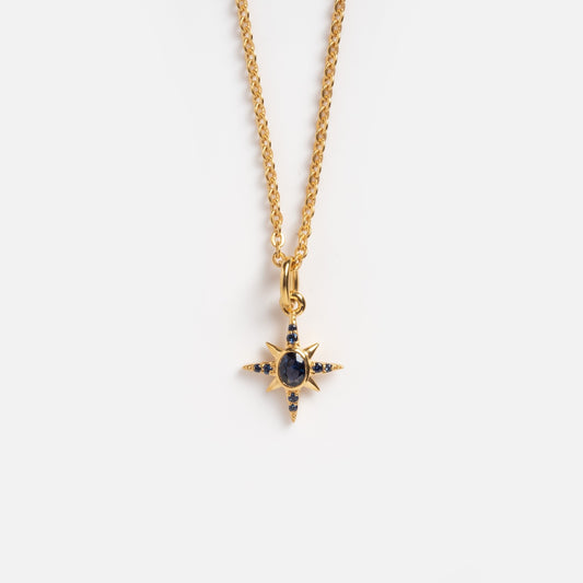 The Celestial Star Necklace Sample is a gold chain featuring a star-shaped pendant with blue sapphires, including a central oval stone and smaller gems at each point, plus a handy chain extender, shown on a plain white background.
