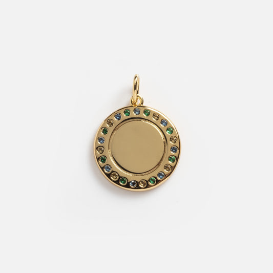 The Classic Gem Coin Charm Sample is a round gold pendant with a blank center, encircled by blue, green, and yellow gemstones, and features a gold loop at the top for attaching to a chain.