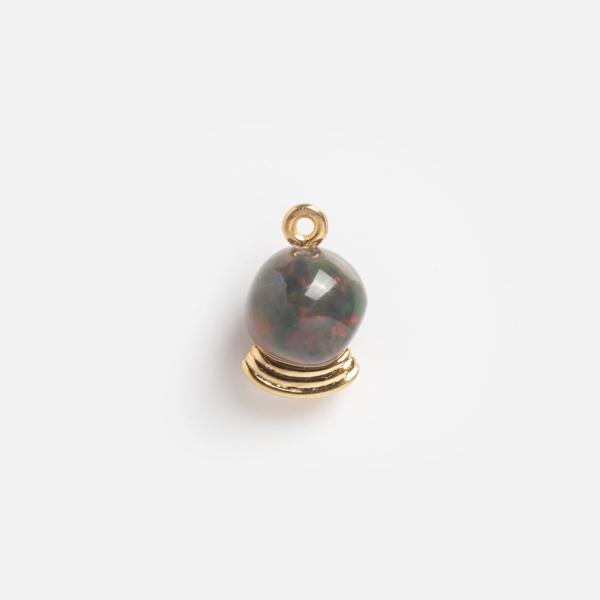 The Solid Gold Opal Crystal Ball Charm Sample features a small gold charm with a round, iridescent opal set on a gold base and a top loop for attaching to jewelry.