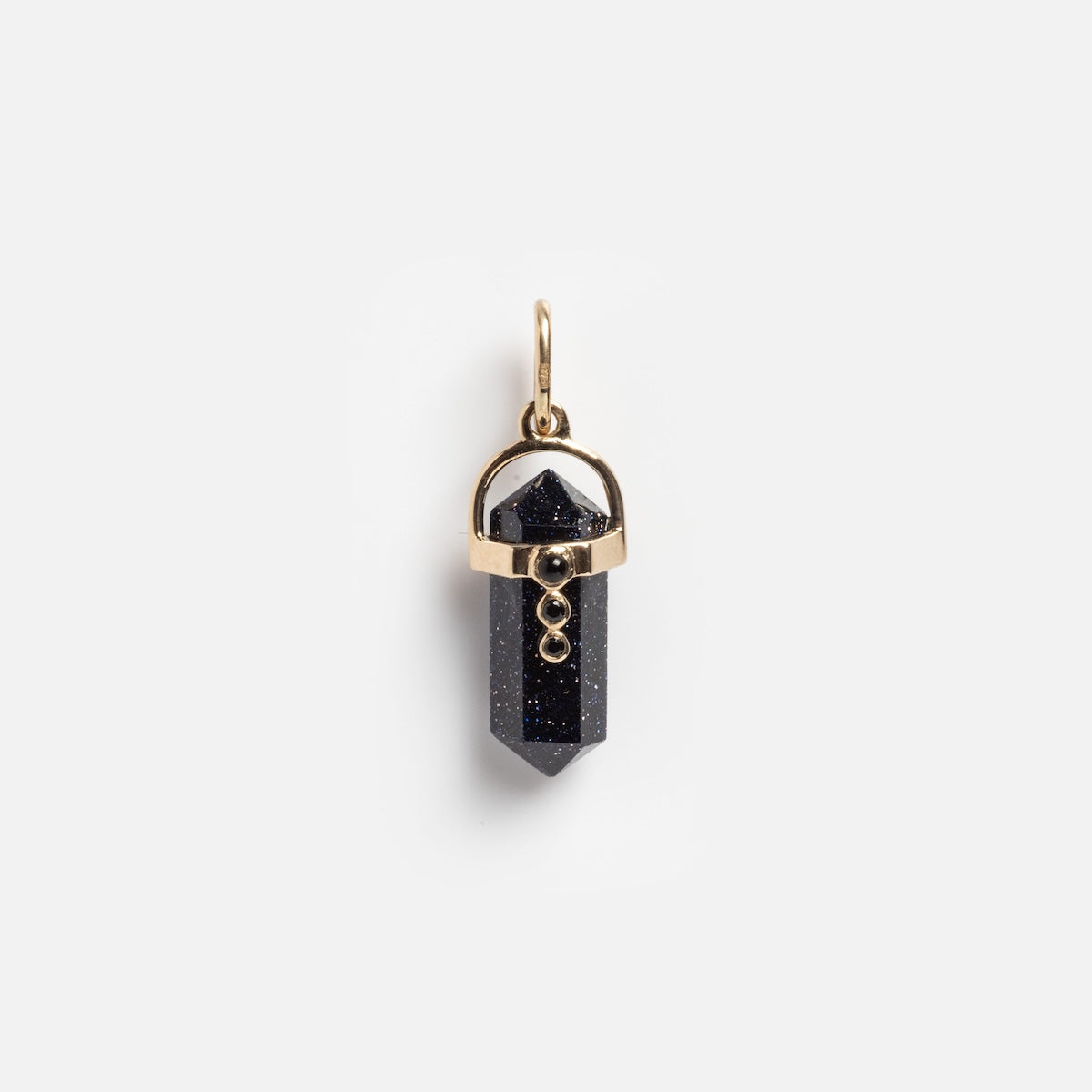 The Solid Gold Opal and Crystal Amulet Charm Sample features a pointed, dark blue crystal with subtle sparkles, accented by three vertically aligned small gold orbs, displayed against a plain white background.