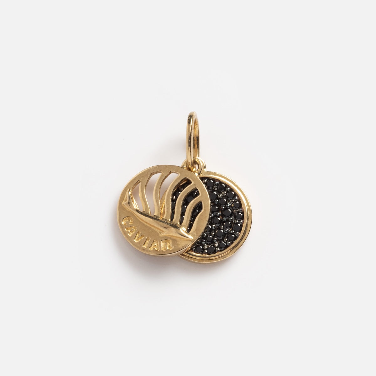 The Solid Gold Caviar Charm Sample is crafted in 9k yellow gold with two overlapping discs: one shows a raised fish and "CAVIAR," while the other features black spinel stones, all displayed on a plain white background.
