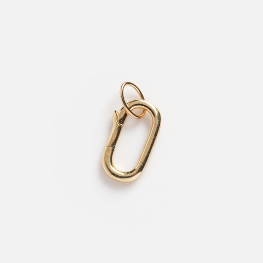 The Solid Gold Oval Charm Clip Sample is a small, gold oval carabiner with a looped ring, shown against a plain white background.