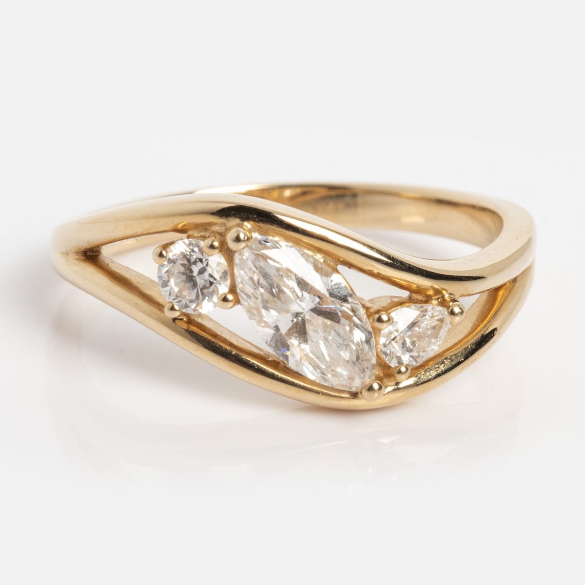 The Solid Gold Floating Diamond Wave Ring (Sample Size 7) features a modern open band in 14k yellow gold, with three lab diamond gemstones of various shapes set diagonally across the center.