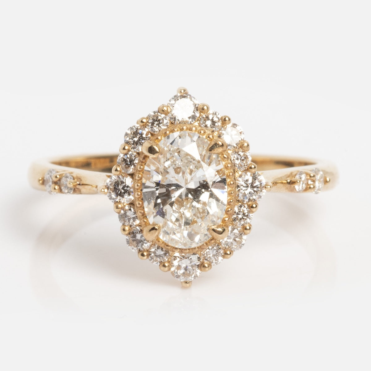 The Solid Gold Pave Halo Diamond Ring (Sample Size 7) features a large oval-cut center diamond, a halo of round diamonds, and additional diamonds along the 14k gold band.
