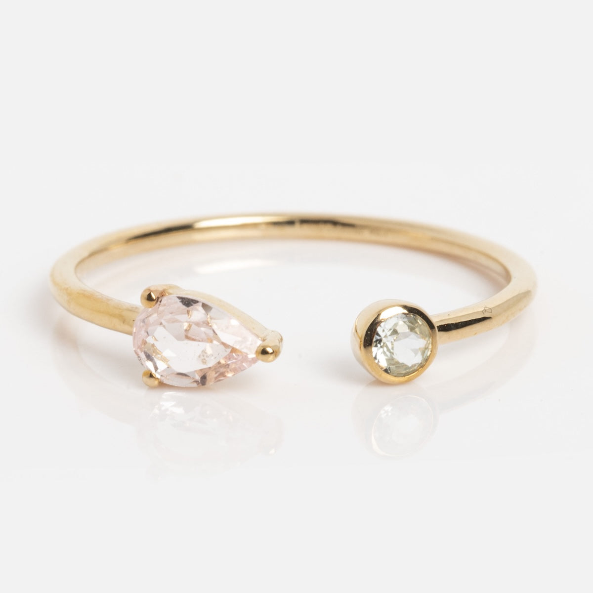 The Solid Gold Pink Sapphire and Aquamarine Open Front Ring (Sample Size 7) features a 9k yellow gold open band with a pear-shaped lab pink sapphire on one end and a round lab aquamarine on the other, set against a plain white background.