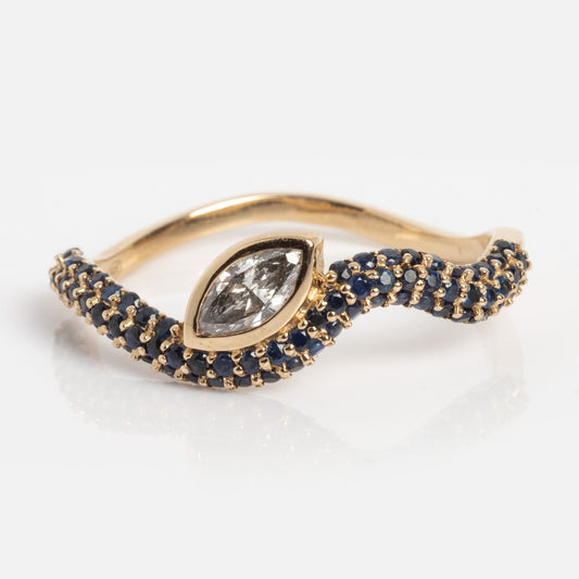 The Solid Gold Marquise Diamond and Blue Sapphire Ring (Sample Size 7) showcases a marquise-cut lab diamond center, accented by blue sapphires on a wavy 14k yellow gold band.