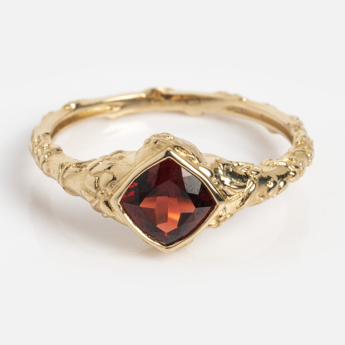 The Solid Gold Classic Garnet Ring Sample Size 7 is crafted in 9k yellow gold with an ornate, textured band and a square-cut deep red Garnet centerpiece. It features a vintage-inspired, intricate design.