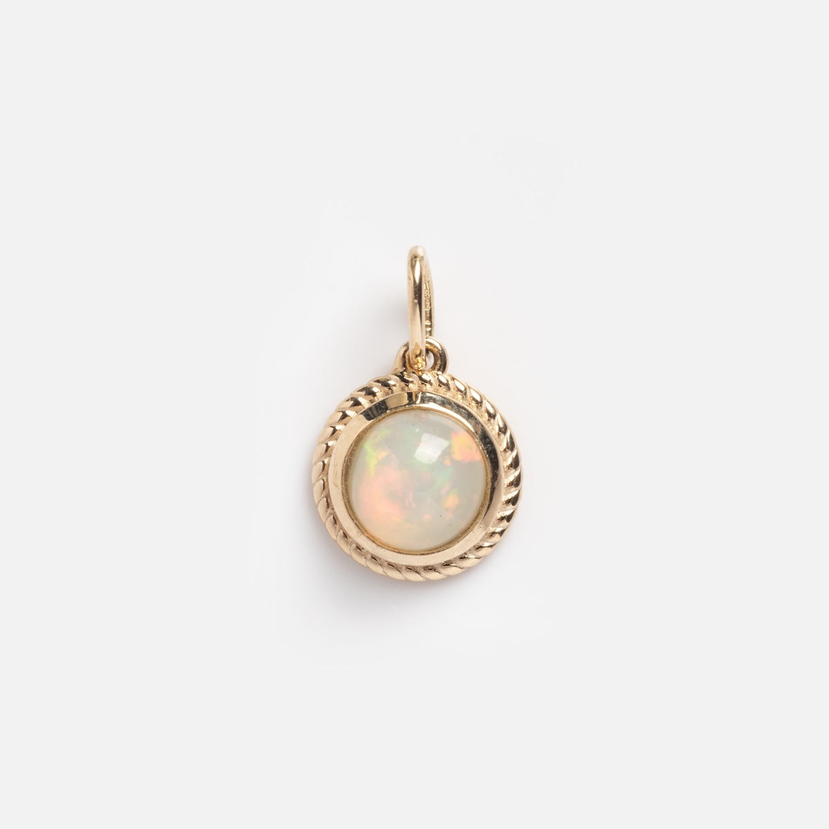 The Solid Gold Bezeled Opal Charm Sample features a round opal with iridescent hues, set in a twisted gold rope bezel and attached to a small gold loop, shown on a plain white background.