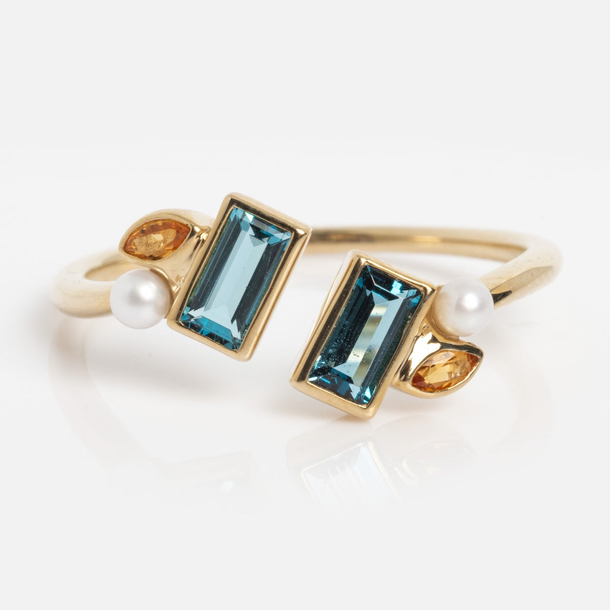 The Solid Gold Open Topaz Tanzanite and Pearl Twist Ring, sample size 7, features rectangular tanzanites, marquise yellow topaz, and round freshwater pearls in an open-ended design, shown against a white background.